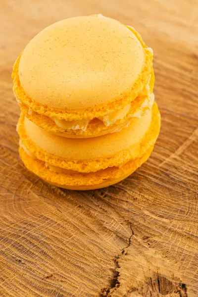 İki canlı turuncu badem kurabiyesi kırsal bir ahşap masaya güzelce istiflenir. Pürüzsüz yüzeyleri ışıldıyor ve hoş dokularına daha yakından bakmalarını sağlıyor..