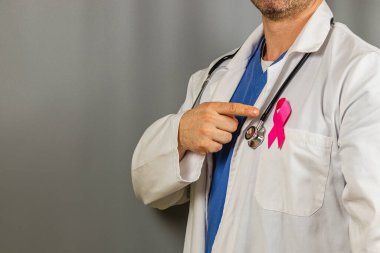 Sağlık uzmanları önlüklerindeki pembe kurdeleyi göstererek meme kanserine karşı farkındalık yaratıyor. Şu anda klinik bir ortamda davaya verilen desteğin altını çiziyoruz..
