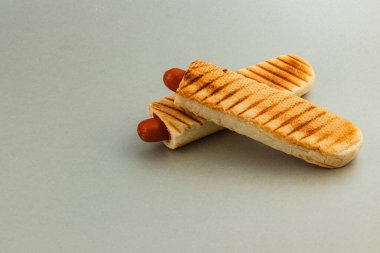 Izgara sosisliler kızarmış ekmeğin üzerine özel ızgara işaretleri ile yerleştiriliyor, basit ama iştah açıcı bir mutfak yaratımı sunuluyor..