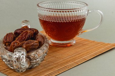 Lezzetli hurmalar bir fincan zengin çayın yanında bir kristal kasede sergilenir. Ayar bambu bir paspas içeriyor, rahat bir yemek atmosferi yaratıyor..