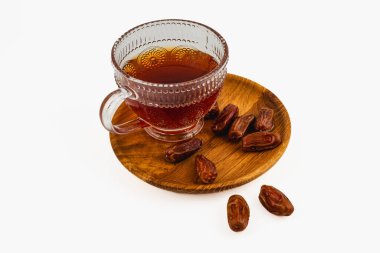 Güzel işlenmiş bir bardak çay taze hurma dolu ahşap bir tabağın yanında oturur. Sıcak renkler davetkar ve geleneksel bir ortam yaratır..