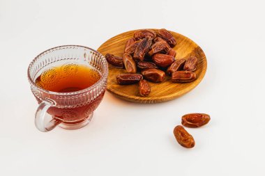 Bir bardak aromatik çay, tatlı, dolgun hurma dolu ahşap bir tabağın yanında oturur ve her durum için lezzetli bir aperatif hazırlar..