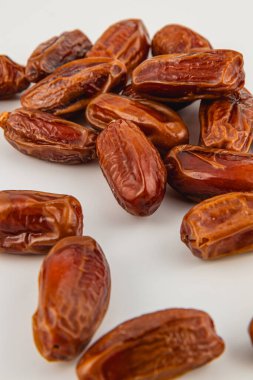 Dolgun, kahverengi hurmalardan oluşan bir derleme pürüzsüz beyaz bir yüzeye saçılmış, doğal tatlılıklarını ve potansiyel tarifler ve atıştırmalıklar için davetkar dokularını sergiliyor..
