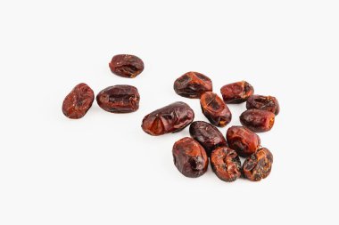 Açık bir yüzeye dağılmış kurumuş hurmalardan oluşan bir derleme zengin kahverengi renklerini ve buruşuk dokularını sergiliyor. Sağlıklı bir atıştırmalık ya da malzeme için ideal..