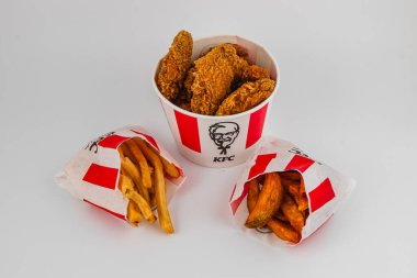 Lviv Ukrayna 05.21.25 Çıtır kızarmış tavuk parçaları klasik bir kovada sunuluyor, yanında da fast food restoranından kızarmış patates ve patates kızartması..