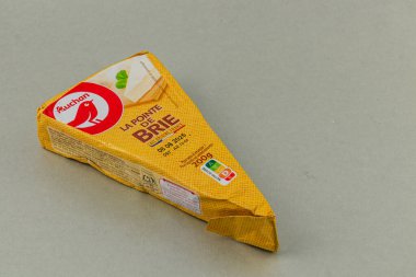 Lviv Ukrayna 05.22.25 Bir paket Brie peyniri pürüzsüz gri mutfak tezgahında duruyor. Peynir kısmen görülebilir, kremsi dokusunu vurguluyor..