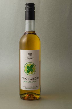 Bir şişe Pinot Grigio, ferahlatıcı bir kireç ve nane karışımı içeriyor, canlı rengini ve çekici etiket tasarımını gözler önüne seren basit bir arkaplan karşısında duruyor..
