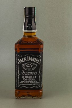 Tanınmış bir viski şişesi dik duruyor ve kendine özgü etiketini gösteriyor. Kehribar sıvısı ve ikonik damga, onun kalıtımını ve işçiliğini gösteriyor..