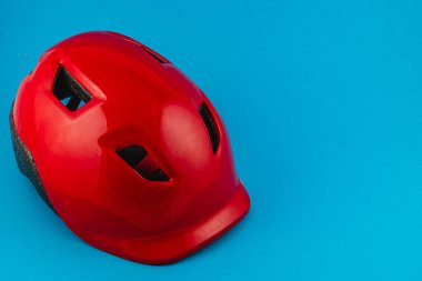 Lviv Ukrayna 05.22.25 Parlak bir kırmızı güvenlik kaskı, bisiklet, tırmanma veya diğer açık hava sporları için ideal tasarımını sergileyen mavi bir zemine dayanır..