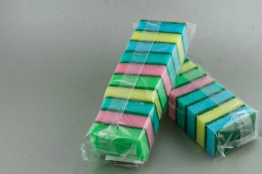 Lviv Ukrayna 05.22.25 Sünger paketleri canlı renkler düzgünce dizildi. Süngerlerde yeşil, pembe, sarı ve mavi çizgiler var. Ev temizlik işleri için ideal..