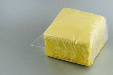 Lviv Ukrayna 05.22.25 Gri masaya bir yığın sarı peçete konur. Peçeteler şeffaf plastiğe sarılıp akşam yemeği veya etkinlikleri için kullanılmaya hazır hale getiriliyor..