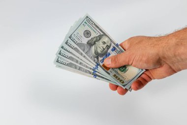 Bir el, bir kaç yüz dolarlık banknotları elinde tutar. Gıcır gıcır banknotlar sıkıca bir araya toplanmış, intaglio baskı ve taze dokularını sergiliyorlar..