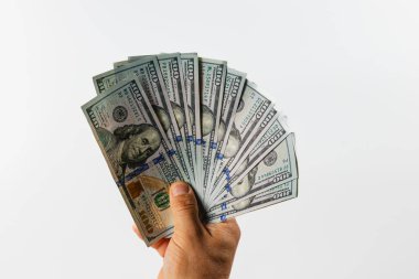 Tarafsız bir arkaplanda yüz dolarlık banknotların hayranını gösteren bir el. Detaylı para birimi, banknotların tipik canlı desenlerini ve dokularını gösterir..