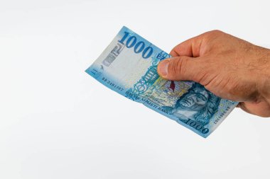 Para biriminin tasarımı ve detaylarını vurgulayan bir el, düz bir arkaplan karşısında 1000 'lik banknotu kavrarken gösteriliyor. Bu para işleme eylemini yakalar..