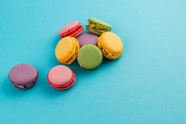 Renkli badem kurabiyelerinin hoş bir çeşidi canlı mavi bir arka planda bulunur. Pembe, sarı, yeşil, mor ve turuncu renkler sergilenir. Tatlı aşıkları için mükemmeldir..