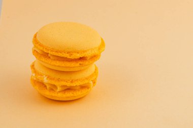 Yumuşak pastel bir yüzeye istiflenmiş iki canlı sarı badem kurabiyesi pürüzsüz dokularını ve neşeli renklerini sergiliyor..