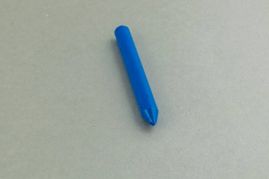 A bright blue crayon rolls and bounces playfully on a smooth, light-colored surface, showcasing its vibrant hue and playful motion during the activity.