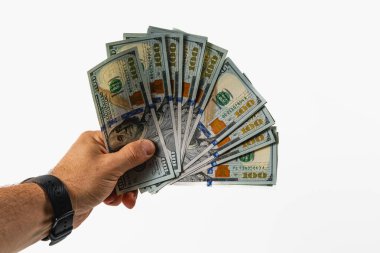 A hand is displaying a fan of hundred dollar bills in front of a neutral gray background, showcasing the intricacies of U.S. currency in an elegant manner.