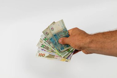 A hand displays an assortment of banknotes in various denominations, highlighting the value and diversity of currency. The setting is neutral with a simple backdrop.