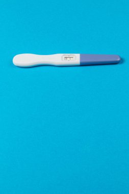 A pregnancy test lies flat on a vibrant blue background, showcasing its results clearly. The clean design highlights the crucial moment for expectant individuals.