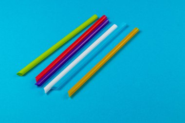 Çeşitli renkli pipetler parlak mavi bir arka planda yatıyordu, canlı renklerini sergiliyorlardı, el işi faaliyetleri veya parti dekorasyonları için mükemmeldiler..