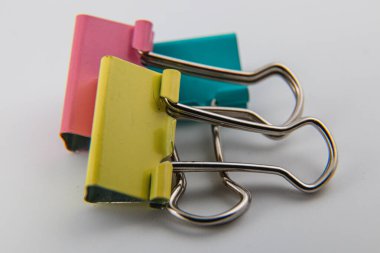 Pembe, yeşil ve sarı renkli parlak cilt klipleri pürüzsüz bir yüzey üzerinde, canlı renklerini ve ofis veya okul kullanımı için ideal fonksiyonel tasarımı sergiliyorlar..