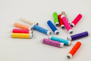 Değişik renklerde birden fazla iplik makarası beyaz bir yüzeye dağılmış. Bu da yaratıcı bir zanaat faaliyeti olduğunu gösteriyor..