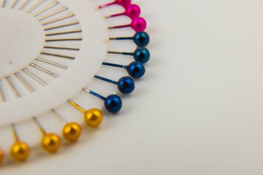 Brightly colored pins are displayed in a circular holder, showcasing shades of pink, blue, and gold. Ideal for sewing and crafting enthusiasts.