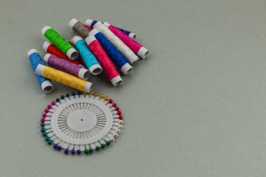 Parlak renkli iplik makaraları, canlı iğnelerle dolu dairesel bir tutucunun yanında düzenlenerek, el işi ve dikiş faaliyetleri için davetkar bir atmosfer yaratılıyor..