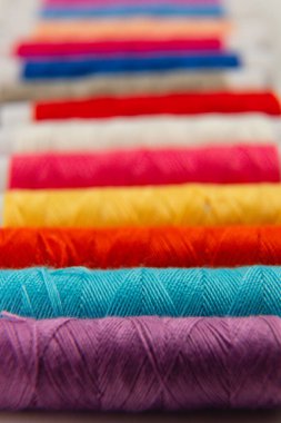 A collection of vibrant spools of thread in various colors lined up neatly on a table, perfect for sewing enthusiasts or craft projects in a creative workspace.
