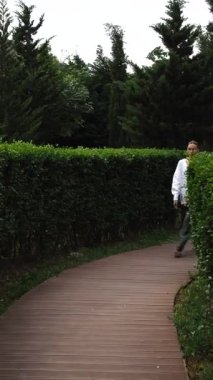 Uzun boylu kadın manken, şehir parkında podyumda yürürken keten giysilerini gösteriyor.