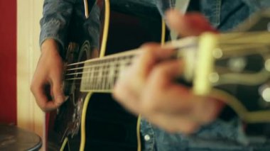 Bir erkeğin elinin akustik gitarın fretboard 'unda akorları çaldığı yakın plan.