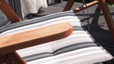 Dağ manzaralı bir otel kabininin balkonunda çizgili yastıklı koltuklar.