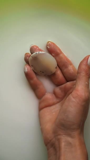 女孩从乳白色的液体中取出Agate石子 用手指握住它 — 图库视频影像