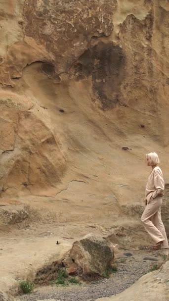 環境に優しいリネンスーツの女性は 服を脱いで山の壁に沿って歩きます — ストック動画