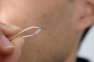 Bir adam cımbızla sakalını çekiyor.