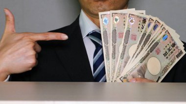 Banknotları tutan ve işaret eden bir işadamı