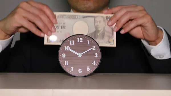 Saatin önünde banknotları olan bir iş adamı.