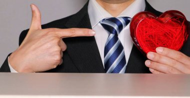 Bir iş adamı bir kalp tutuyor ve işaret ediyor.