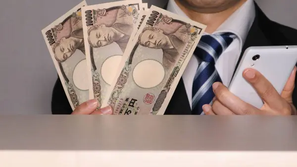 Banknotları ve akıllı telefonu olan bir iş adamı.