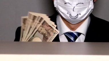 Gülümseyen bir iş adamının kendini banknotlarla yelpazelemesi.