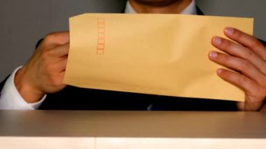 Şaşırmış iş adamı zarftan banknotları çıkarıyor.