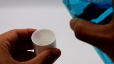 Bir insan bardağa gargara dolduruyor.