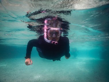 Güzel bir yaz tatilinde nehrin yüzeyinde şnorkelle yüzen bir kız. Kristal berrak, şeffaf mavi nehir.
