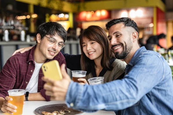 Çok Irklı Arkadaşlar Bira Bardağında Oturmuş Akıllı Telefonlarıyla Selfie Çekerken — Stok fotoğraf
