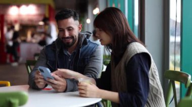 Çok ırklı bir çift, o akıllı telefonuyla bir kafede birlikte vakit geçiriyorlar.