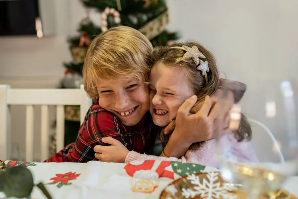 happy sibling children hug at christmas dinner