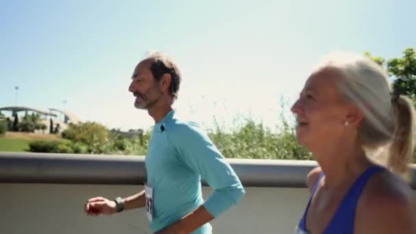Pelari Senior Dengan Bib Nomor Memenangkan Perlombaan Maraton Luar Ruangan — Stok Video