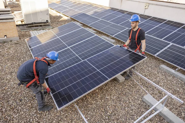 在房顶上安装光电太阳能组件的安装技术人员 — 图库照片