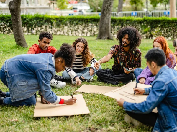 group of young multiracial activists preparing a sign before the outdoor protest